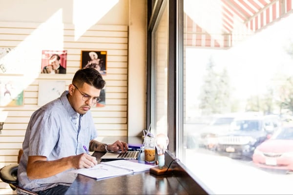 Man sits in cafe working on laptop